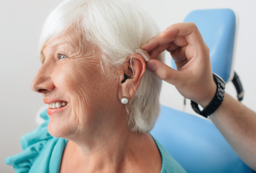 An older woman gets an adjustment made to her hearing aid